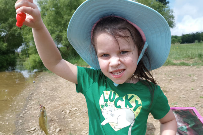 Lila tenant un poisson qu’elle a attrapé