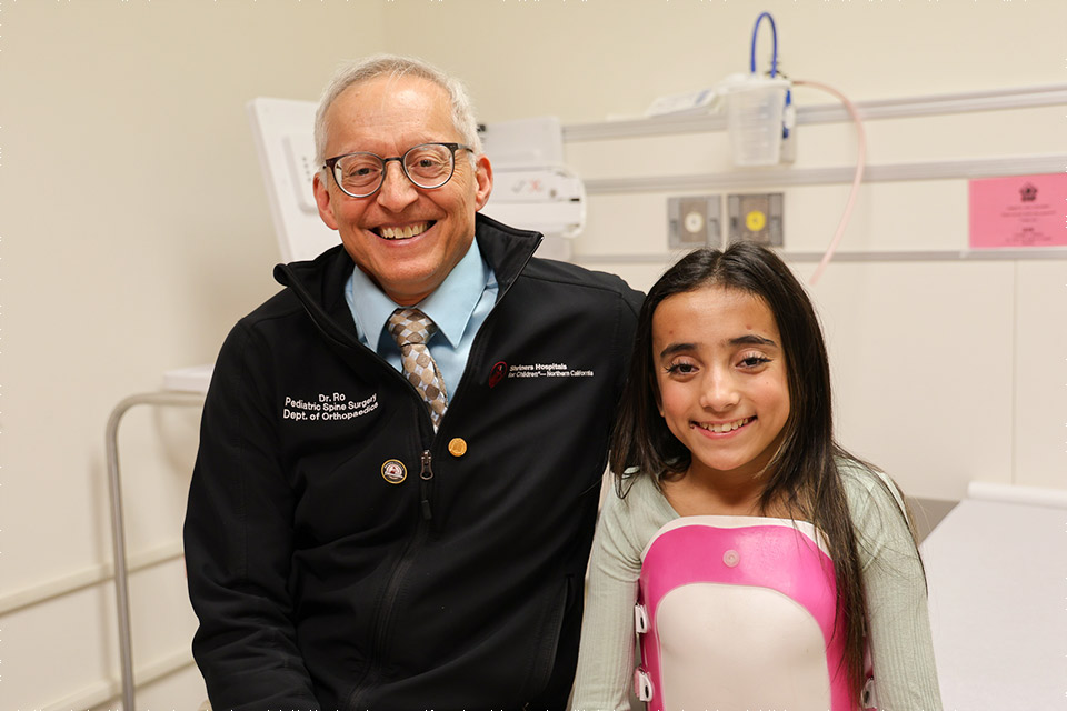 Patient with back brace sitting next to physician, Rolando Roberto, M.D.