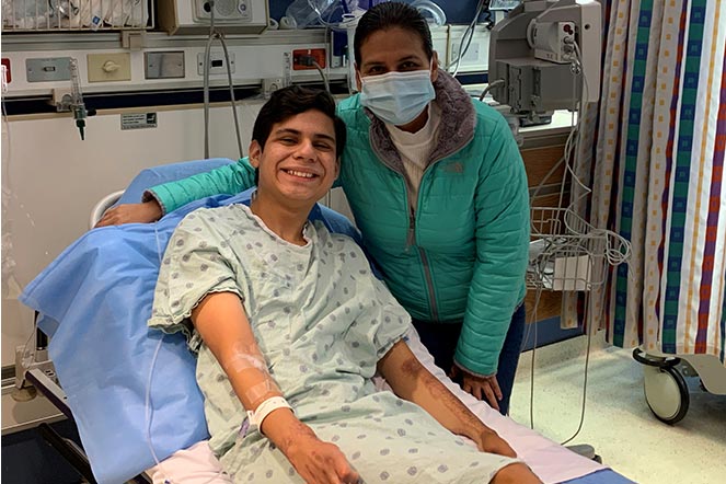 Juan Diego in hospital bed with Jackie standing next to him