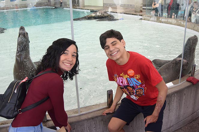 Juan Diego assis avec Valentina à côté d’un enclos de phoques à l’aquarium