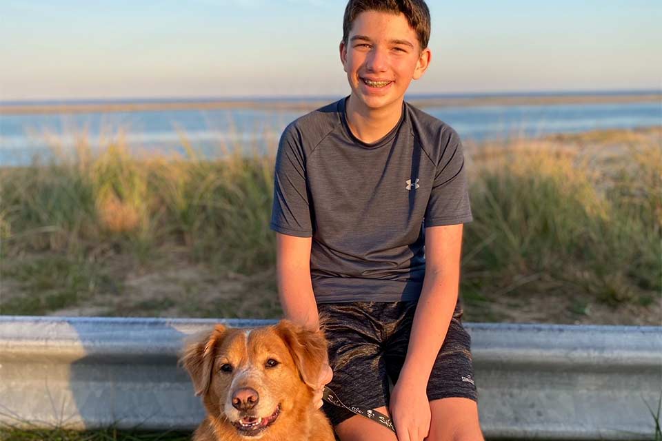 Sawyer y perro de familia sentado afuera en la playa