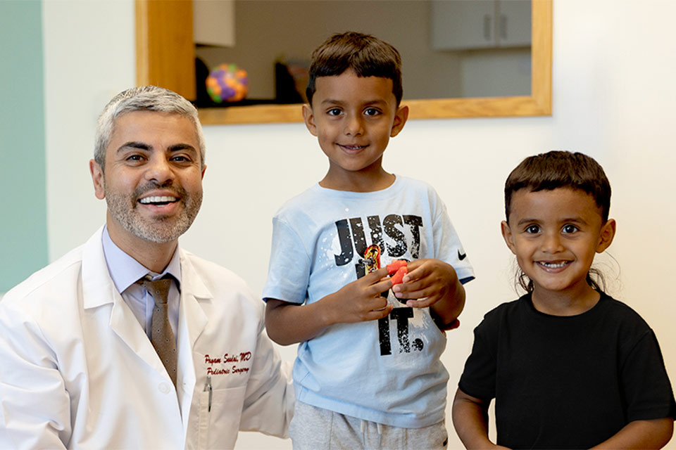 Physician smiling next to two male patients