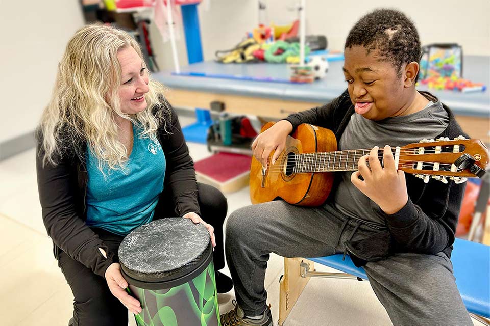 Male patient plays guitar with child life therapist