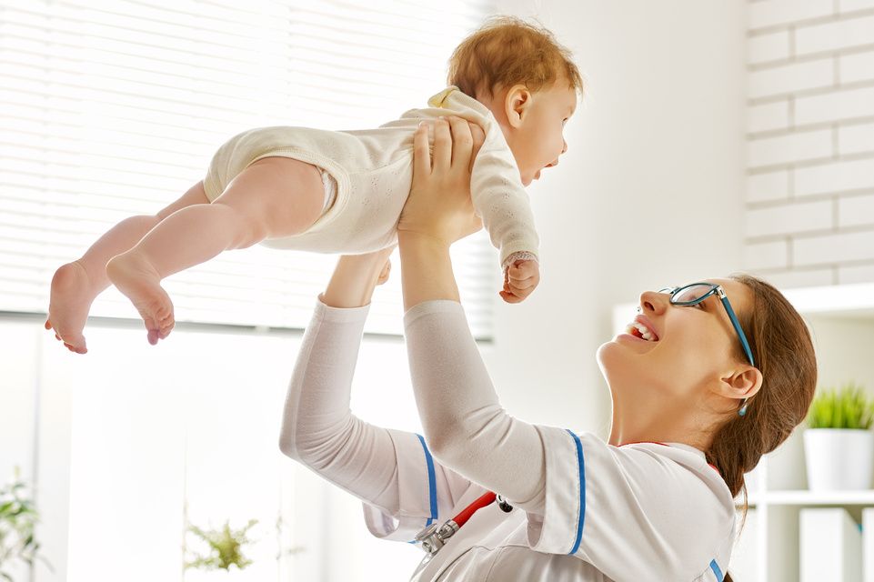 médico sosteniendo a un bebé en el aire