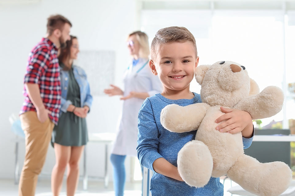 patient holding teddy bear, parents consult with physician