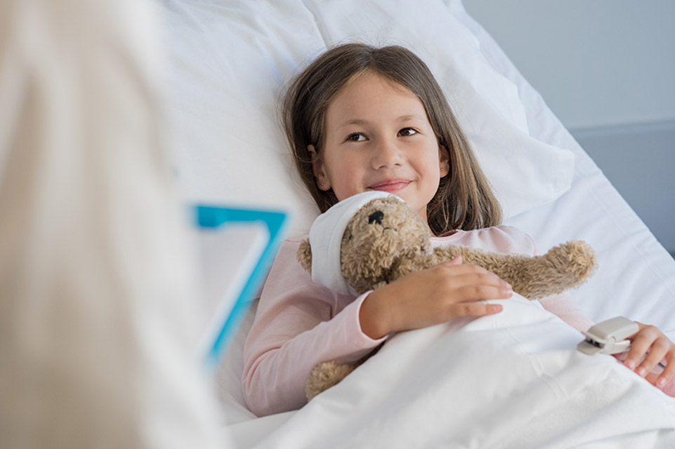 une patiente dans un lit d’hôpital avec un ours en peluche