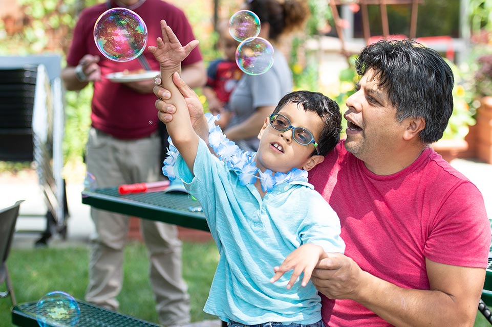 un paciente y su padre jugando con burbujas en el exterior