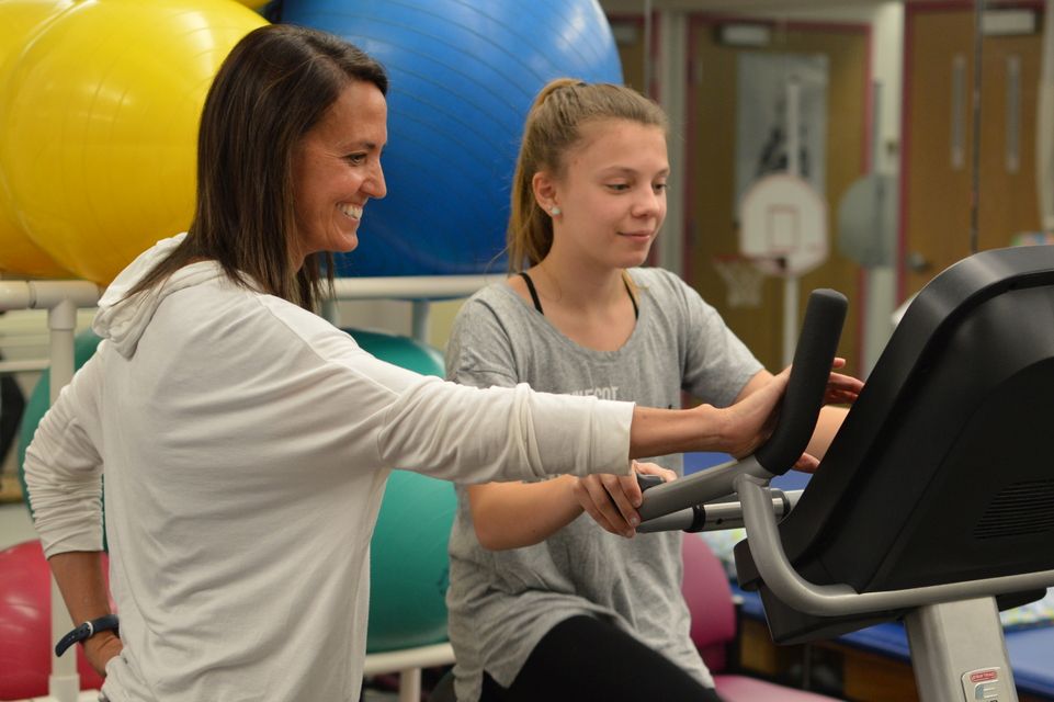 physical therapist works with patient on treadmill