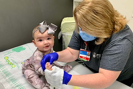 Una enfermera examina la mano de una bebe