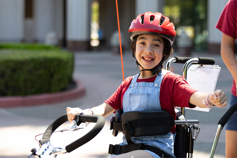Female patient wearing helmet riding adaptive bicycle