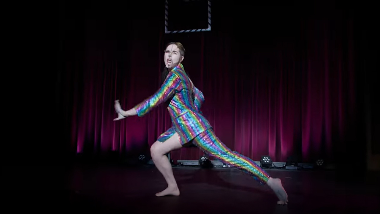 a dancer in a colorful outfit on stage